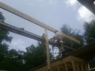 Carpenter setting a ridge beam over a new addition frame — Ice Dam Removal by Roofing Brothers in Henniker
