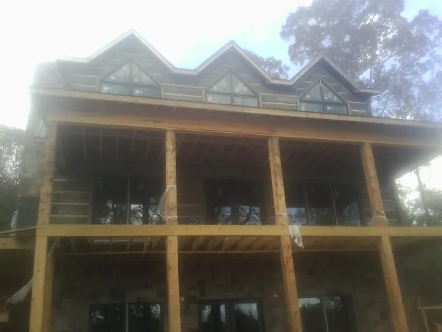 Dormers and porch framing on a large log home under construction — Roof Coating work by our crew in Henniker