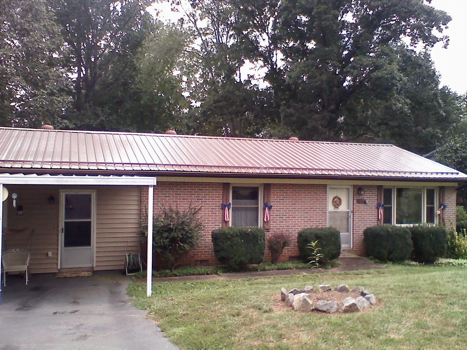 Bronze metal roof and carport on a brick ranch home — Roof Repair work by our crew in Henniker