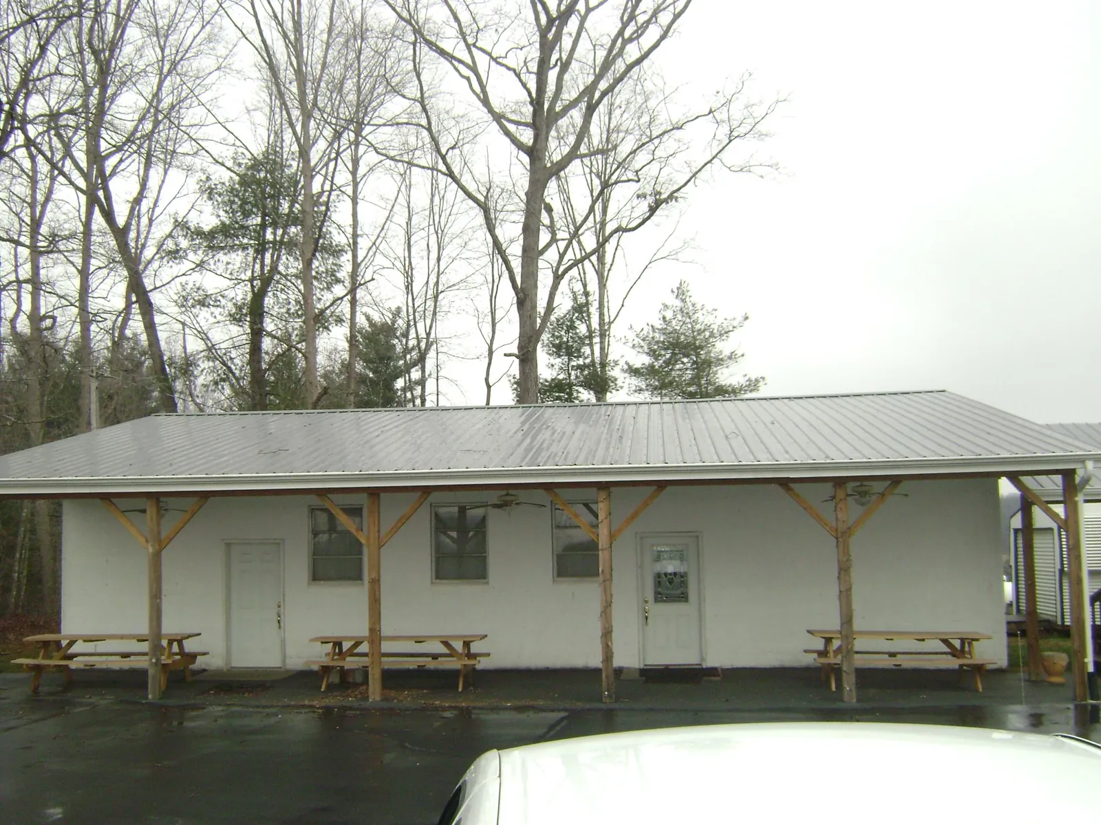 Gray metal roof over a block building with a timber post porch in Henniker