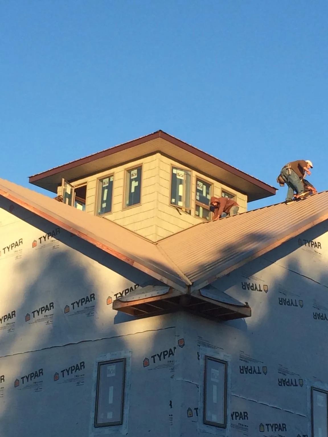 Roofers working around a rooftop cupola on a new metal roof at sunset — Roof Waterproofing in Henniker by Roofing Brothers
